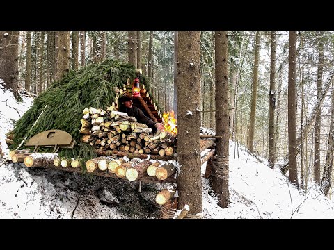 Construction of a comfortable log shelter on the mountainside. Bushcraft in a cold winter forest